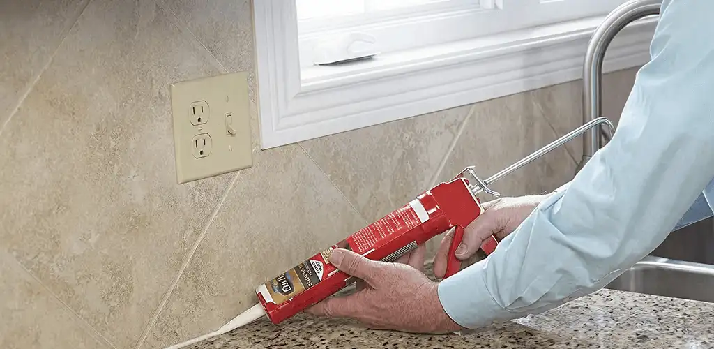 Handyman applying caulk along a kitchen backsplash and countertop seam in Hollywood, FL