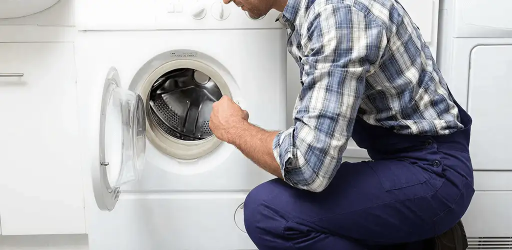 Handyman inspecting a dryer drum and internal parts for repair in Hollywood, FL