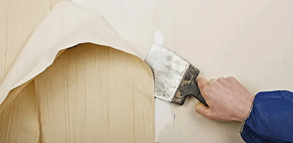 Handyman removing wallpaper with a scraper for wall preparation in Hollywood, FL