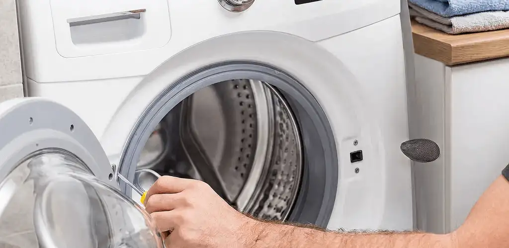 Handyman repairing a front-load washing machine and inspecting the drum in Hollywood, FL