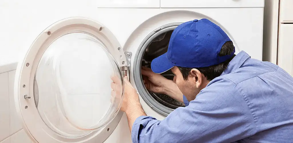 Washing machine repair handyman inspecting a front-load washer drum in Hollywood, FL