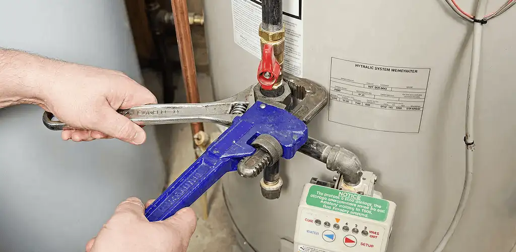 Water heater repair technician tightening the shutoff valve and supply line in Hollywood, FL
